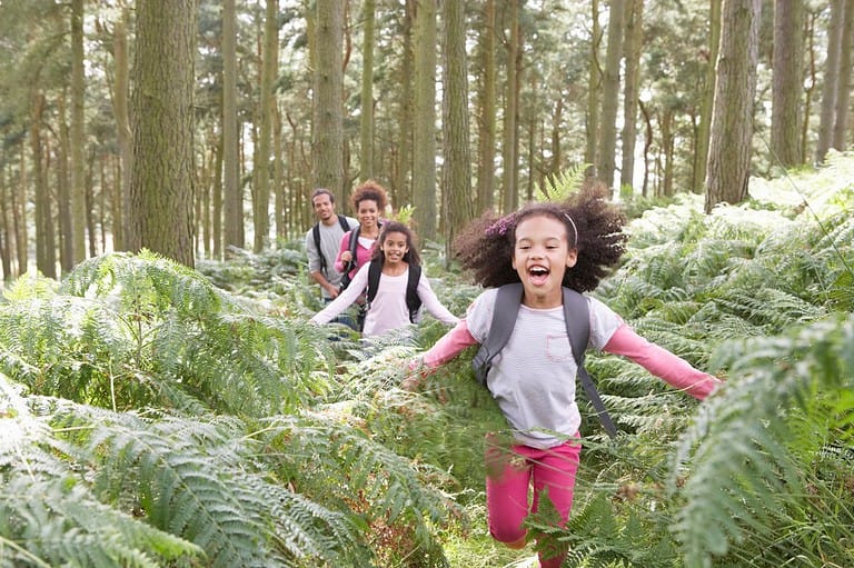 Family having fun hiking in the woods. Explore natural beauty without spending a dime! Discover how with our latest guide to enjoying Minnesota's State Parks for FREE in April 2024.
