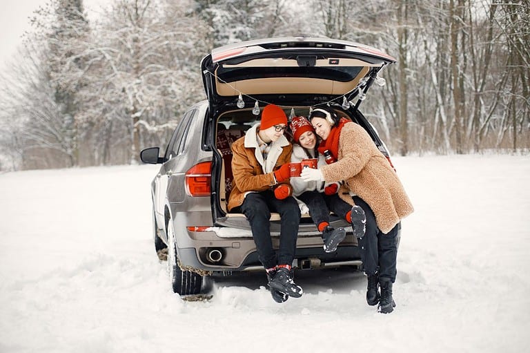 Happy family parked in a snowy scene tailgating in the winter