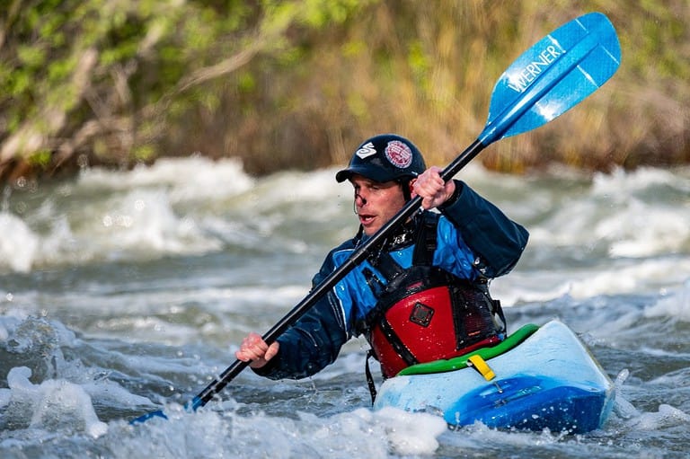 Kayaking in Wisconsin: a great Outdoor Activities in Wisconsin. Man on rushing river paddles hard.