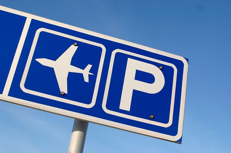 Blue and white sign with symbols for airport parking. Thinking of parking at the airport? Think again! Save your money and your car with these smarter alternatives.