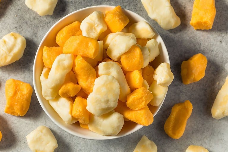 Picture of cheese curds in a bowl on a table. Cheese curds are a big deal in the Midwest, especially in Wisconsin. Discover the yummy world of cheese curds with these surprising facts!