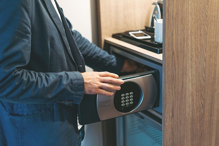 A man uses a hotel room safe. He is well dressed. Why should you put your shoe in the safe? Discover a flight attendant's genius hotel hacks that will change the way you travel!