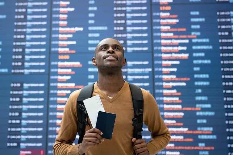 Confident man standing in airport with his passport. He is a frequent flyer.