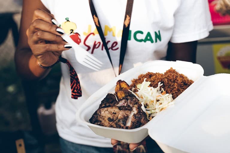 A Jamaican woman eats Jamaican food from Ire Jamaican Express in Minneapolis