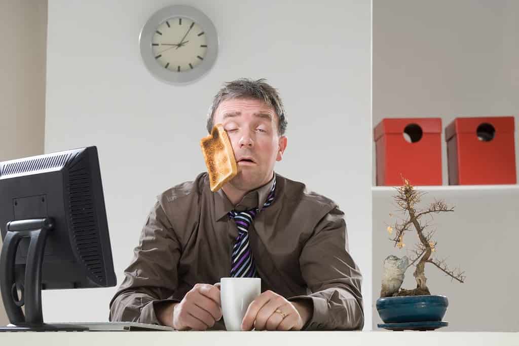 Tired office worker at a desk on a Monday morning representing funny Monday jokes and workweek humor