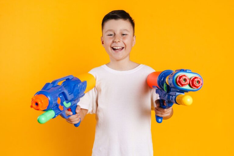Elementary age boy is smiling while holding two Nerf toys at the Nerf indoor fun spot in Minnesota