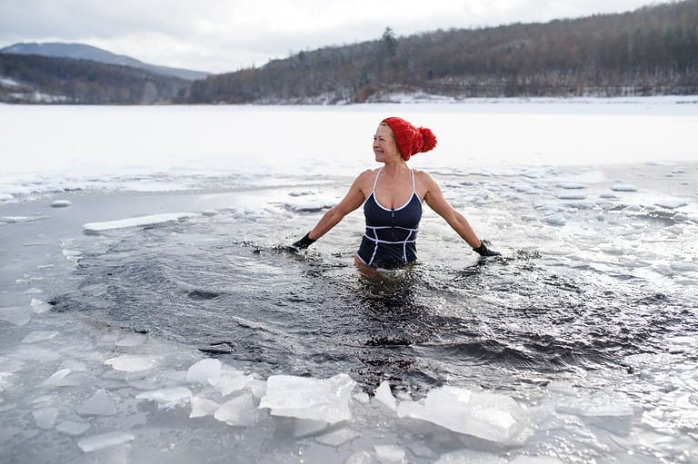 A woman participating in the Polar Plunge - Minnesota's Favorite Winter Tradition. She is jumping into a frozen lake in the winter.