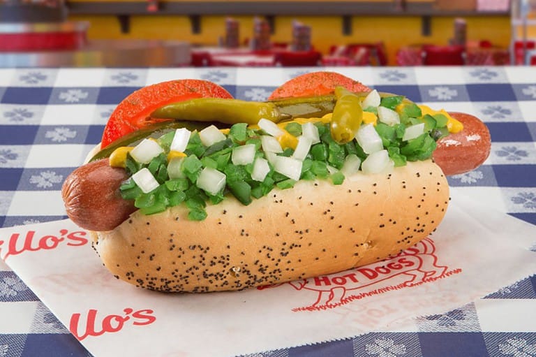 Portillo's hot dog on a table. Delicious looking hot dog with fixings including peppers and onions.