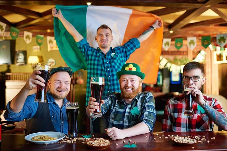 Men celebrating St. Patrick's Day at a Pub. They are dressed in Irish stuff. Get ready to go green! Check out these 9 unmissable St. Patrick's Day events in Minnesota that offer a perfect blend of fun and celebration.