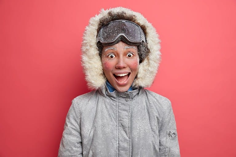 Funny woman laughing at jokes about winter. She is dressed in winter clothing and has a silly expression on her face.