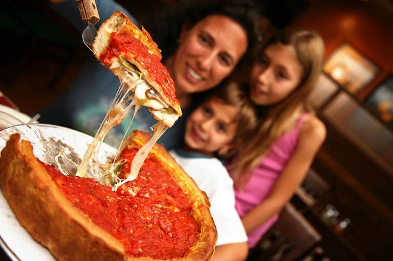 Mom and daughters looking at tasty deep dish pizza. You won't believe the amazing things to do in Chicago! From deep dish pizza to jaw-dropping architecture, the Windy City will blow you away!