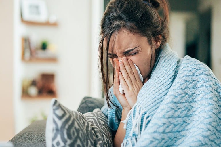 Sick woman blowing her nose. Don't let your hotel room ruin your vacation! A little extra caution can go a long way in keeping you happy and healthy on your next trip.