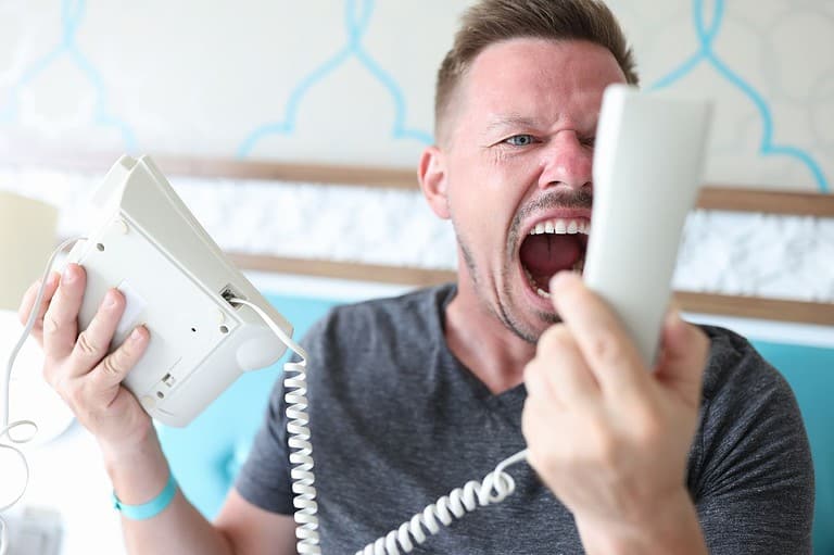 Annoying man screaming into hotel room phone. Want to be the best hotel guest ever? Travel experts suggest five simple tips and tricks so you can enjoy a stress-free stay!