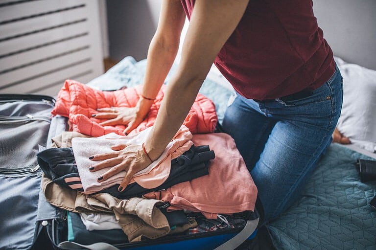 Woman struggling to pack her suitcase. Time for a stress-free travel hack: discover the life-changing secrets to packing light and say goodbye to overpacking forever!