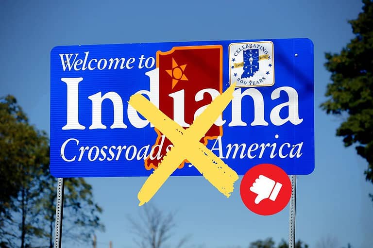 Welcome to Indiana road sign crossed out with emoji of thumbs down. Attention: These are the Top 10 reasons why you should NEVER move to Indiana! Thinking of moving here? Read this first!