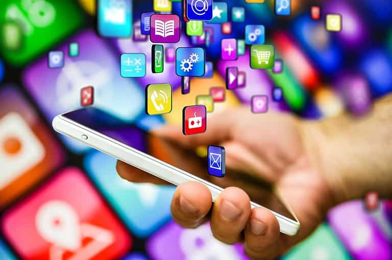 Man holding phone with lots of apps. Don't wanna break the bank? These game-changing apps will help you score unbeatable deals on flights and hotels!