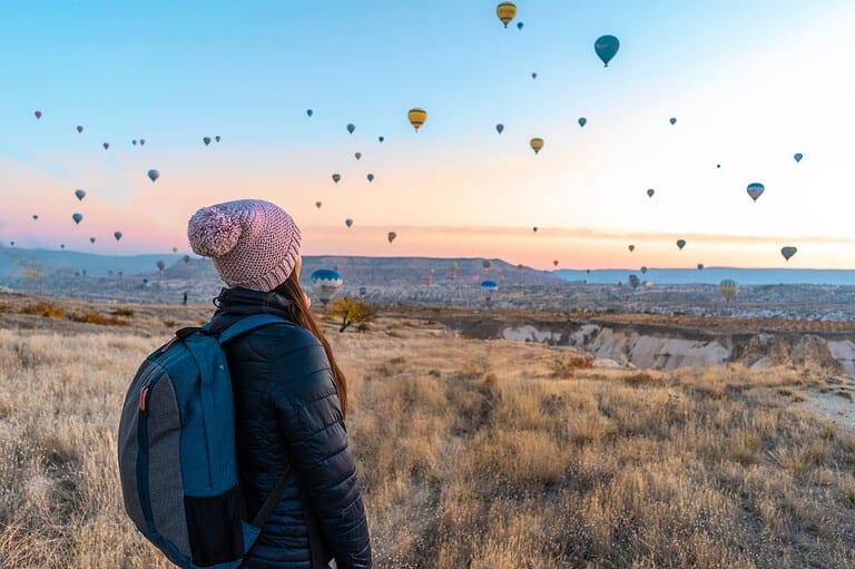 Solo female traveler watching hot air balloons in Wisconsin. Planning an indelible solo Midwest voyage? Learn the secrets to nailing solo travel in the Heartland so you'll be ready to rock this!