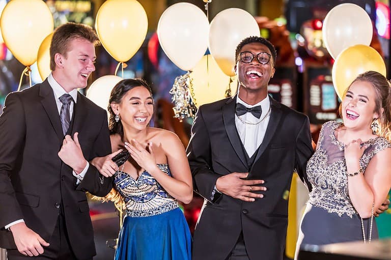 Friends at prom laughing at prom jokes. Get ready to LOL with these hilarious jokes about prom that will make your special night even more memorable!