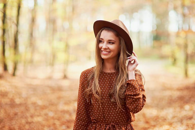 Woman in hat in the woods of Minnesota. Discover the perfect Minnesota city for your zodiac sign! From adventurous Aries to dreamy Pisces, let the stars guide you on your journey.