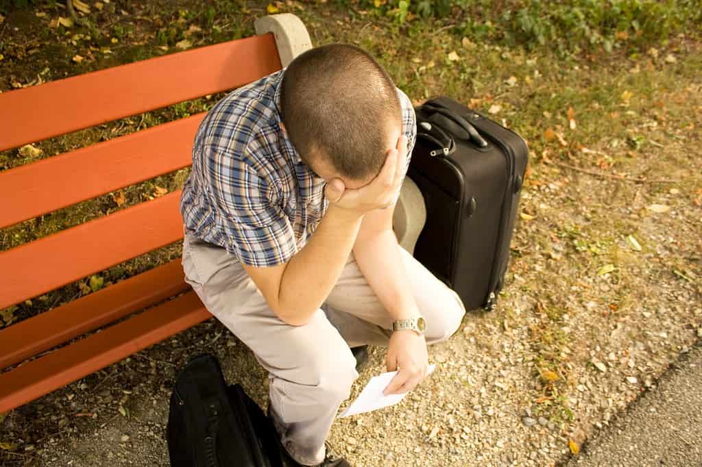 Frustrated Minnesota man with luggage lost in a foreign city.