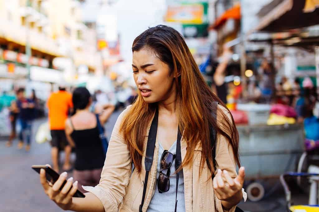 Frustrated Minneapolis woman looking at phone while on vacation.