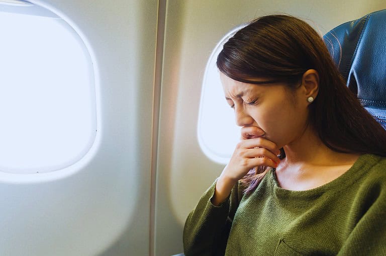 Woman on airplane who is afraid to fly. Discover the secrets to overcoming hodophobia. Learn how to conquer your fear of travel and embrace a world of possibilities.