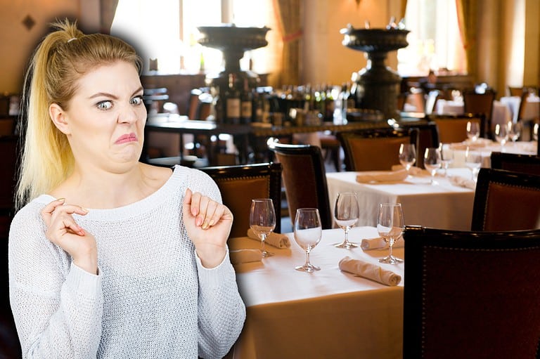 Woman looks disgusted at an empty restaurant. Don't let a bad meal ruin your night out! Learn the telltale signs of a subpar restaurant before you even sit down.