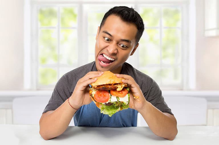 Funny man eating a burger. If you've ever tried to lose weight, you know it's no joke! Keep your spirits high with these relatable weight loss jokes and diet jokes.