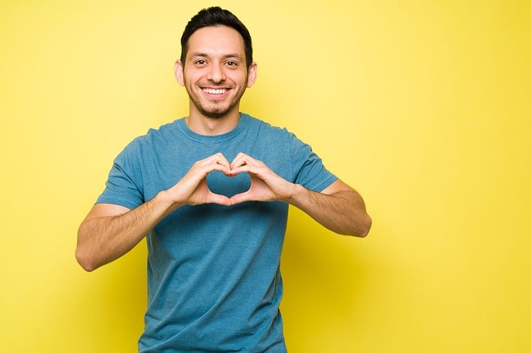 Man holding his hands in a heart over his chest. These are the BEST jokes to cheer someone up and help bring a smile to their face! Get ready to LOL at these funny and cheerful jokes!