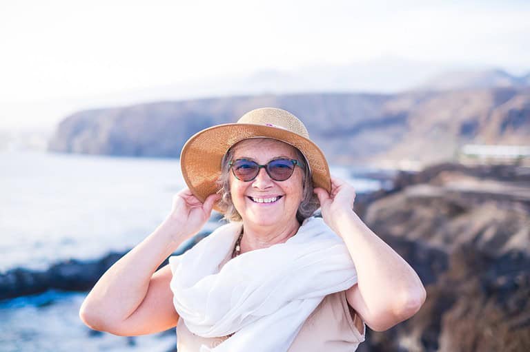 Retired solo female traveler at beach. It's time to embrace adventure and live life to the fullest, avoid these common mistakes and enjoy solo travel in your golden years.