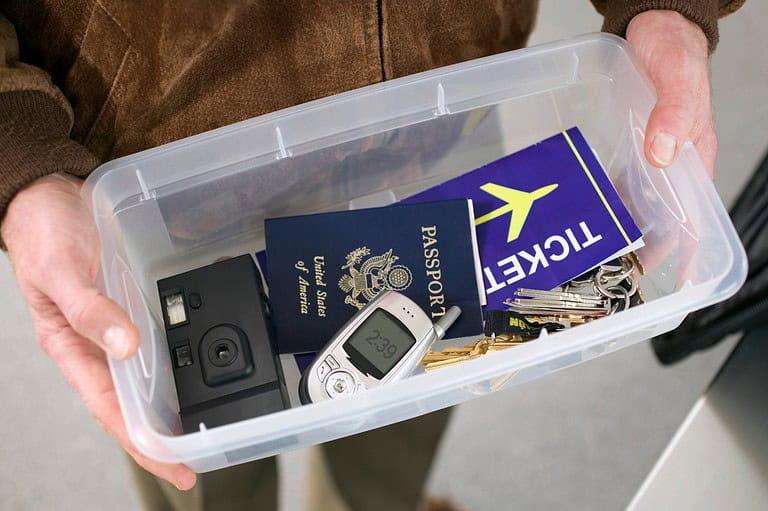 Man holding tray during TSA screening at MSP International Airport in Minnesota. Don't let airport thieves ruin your trip! Learn the secret tricks to keep your belongings safe and secure during the TSA screening.
