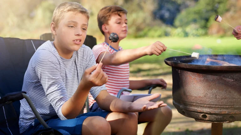 Boy looking at a burnt marshmallow at campfire. Ready to uncover the top camping fails that could wreck your trip? Avoid these common mistakes for a perfect outdoor adventure!