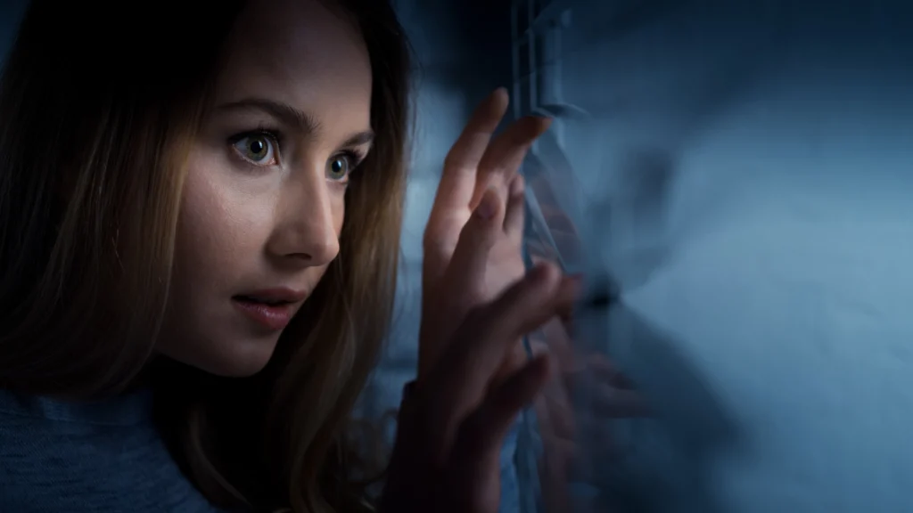 Scared woman looking out window in to the darkness