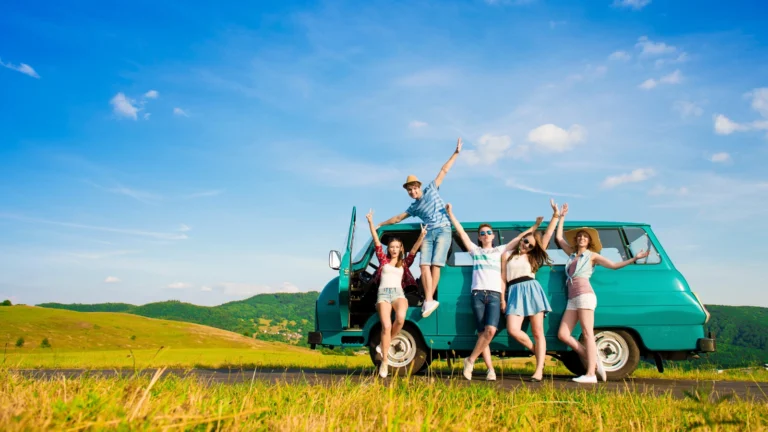 Group of friends on a road trip, taking a picture on a road. Get ready for a smooth journey with these handy tips for preparing your vehicle, packing smartly, using helpful apps, and staying comfy.